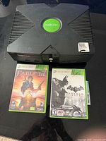 Top view of original Xbox console with two Xbox 360 game cases