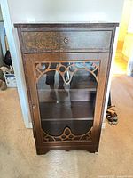Front view of wood and glass display cabinet with decorative fretwork door