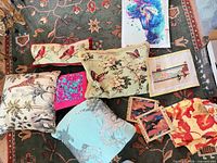 Group shot of assorted pillows, sequin piece, needlepoint items, coasters and fabric panel