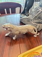 Cast metal silver-tone tiger figurine alongside base of panther sculpture