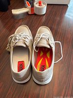 Top view showing pair of beige boat shoes, laces, insoles marked red/yellow