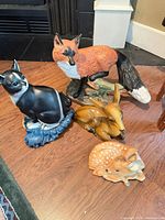 Group shot of four ceramic animal figurines on wood floor