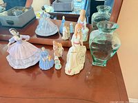 Group shot showing all porcelain figurines and both glass vases
