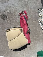 Camping chair in red carry bag and rolled sleeping bag on ground