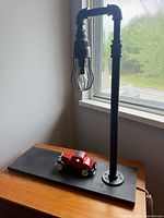 Full view of pipe table lamp on wood base with model car