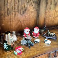 Group shot on shelf showing Santa figures, animal figurines, floral bud vase, metal goblets
