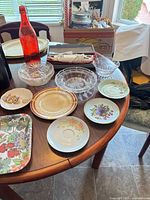 Overview of table showing plates, glass bowls, red bottle, trays and boxed mixer