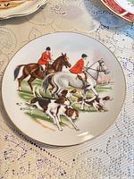 Round plate showing riders, horses and hounds on white base, gold edge