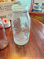 front view of embossed Crown glass jar with lid and portion of purple bottle