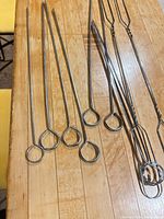 View of single-prong skewers and part of forks on wood surface