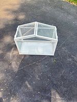 Front angled view showing overall greenhouse structure, glass panels, white frame