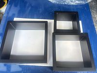 Three black cube shelves of different sizes on tabletop