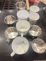 Top view showing all nine mugs, mix of enamel and stainless