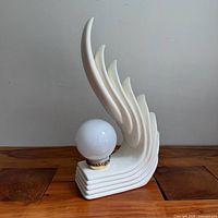 Front view of white ceramic wing/flame lamp with globe shade