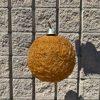 Full view of orange spaghetti globe lamp hanging