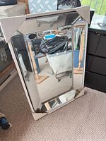 Front view of mirror with protective corner covers showing reflective frame and central glass
