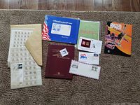 Overview of all contents laid out: albums, stamp sheets in sleeves, manila envelope, first day covers