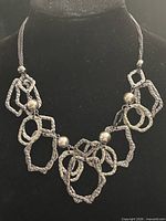 Full view of necklace on bust showing geometric hammered links and bead accents