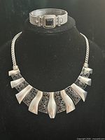 Necklace displayed with matching bracelet on stand