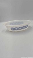 Side view of oval Glasbake milk glass dish showing blue geometric band and handles