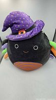Front view of Gildie Squishmallow showing face, hat, striped belly