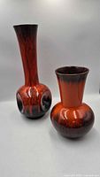 Front view showing both orange drip-glaze vases, differing heights and shapes