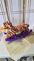 Side view of plush Tigger on purple rocking base