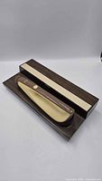 Knife in open wood case showing handle color and box design