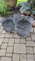 Two ornate metal lattice planters of different sizes on patio