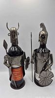 Front view of both metal wine bottle holders displaying Viking and knight designs