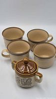 Four mugs and lidded sugar jar front view