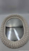 Front view of oval white wicker mirror