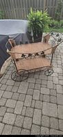Full view of two-tier wicker and metal bar cart on patio