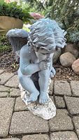 Full view of the large winged cherub statue showing pose, color and condition