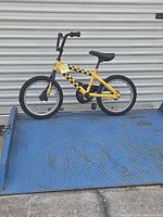 Full side view of yellow and black 16-inch kids bicycle on blue dock