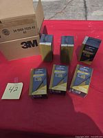 Six boxed 3M SandBlaster Pro sanding sponges beside 3M shipping carton