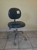 Front view of blue vinyl adjustable desk chair on chrome five-leg caster base, sticky note with number visible