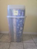 Tall clear tub containing multiple wrapping paper rolls