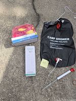 All lot items laid out: camp shower, immersion heater box, Trueliving kids dinnerware set, siphon pump