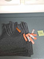 Stack of gray ribbed cropped tank bralettes with hang tags visible