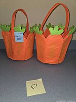Two orange felt carrot-shaped baskets with green felt tops