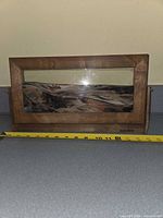 Front view of wood-framed kinetic sand picture with measuring tape indicating width about 13 in