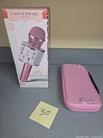 Boxed FAO Schwarz karaoke microphone alongside pink carrying case
