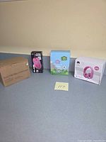 Four boxed items aligned: brown balloon pump box, iJoy Blaze mouse box, blue children’s camera box, white Rockpapa headphones box