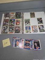 open binder showing multiple football cards in nine-pocket pages and loose stack nearby