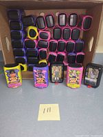 Bulk carton holding rows of pink, purple and black SBZ blind capsules with five sample figures displayed in front.