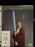 Full view of signed 8x10 photo in sleeve with MaxSold tag and hologram