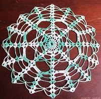 full view of round green and white crochet doily