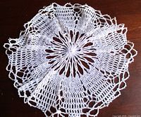 Full view of white crochet doily on wooden surface
