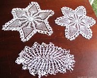 Group shot of all three white crochet doilies on tabletop